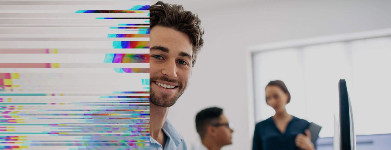 young man smiles with colleagues in background