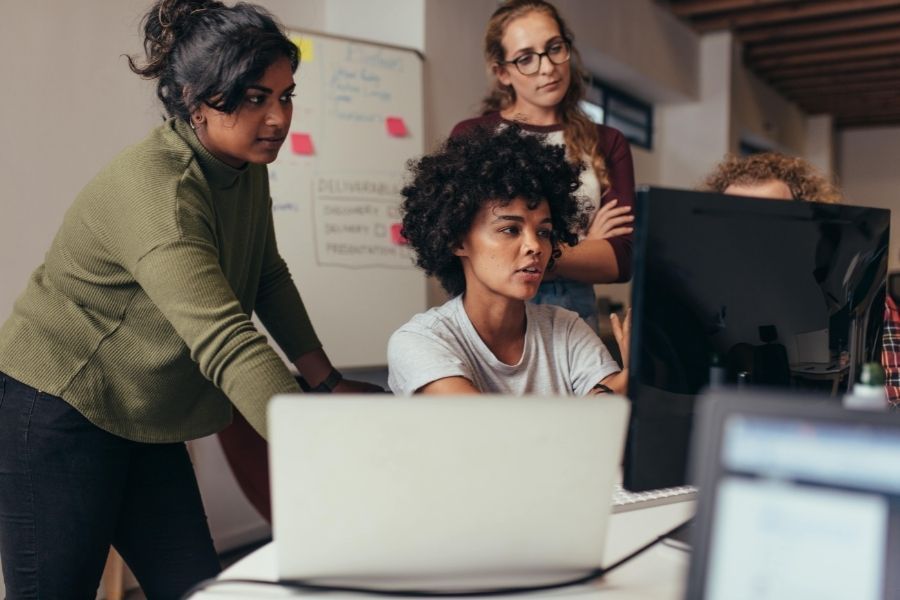 drei IT Experten am Schreibtisch suchen nach Lösungen